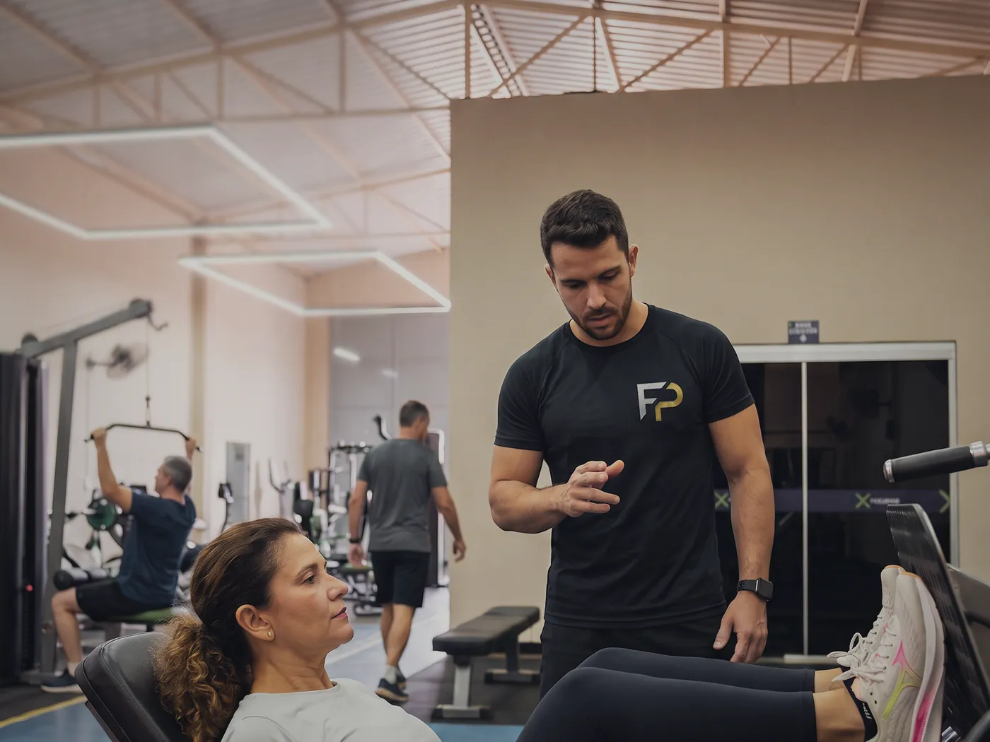 Sala de musculação da Unidade 1 — João XXIII, com professor acompanhando um aluno